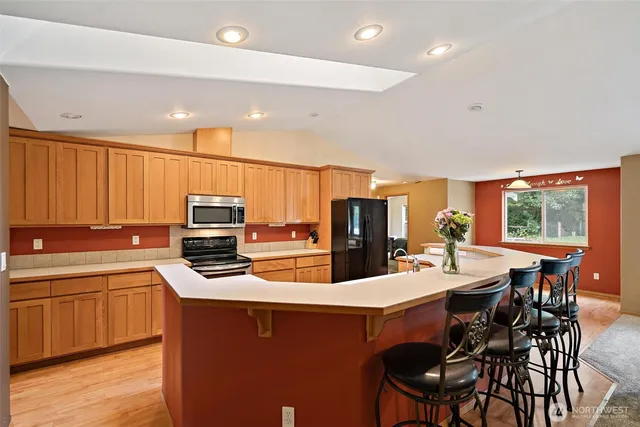 a kitchen with stainless steel appliances a sink a stove a refrigerator cabinets and dining table
