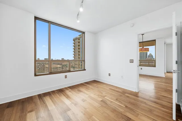 a view of a room with a large window and wooden floor
