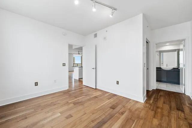 a view of an empty room with wooden floor and a window