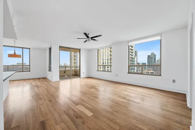 a view of an empty room with a window and wooden floor