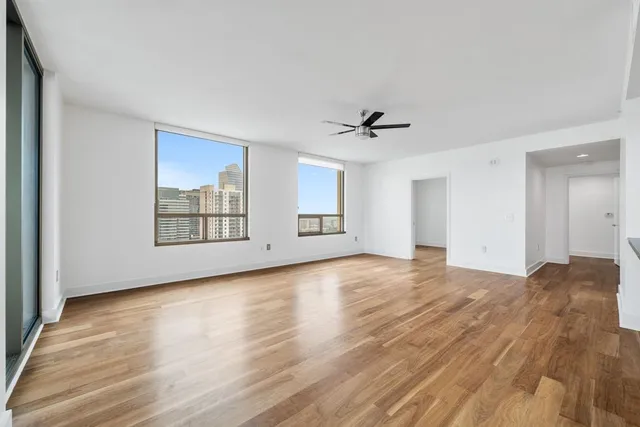a view of empty room with wooden floor and fan