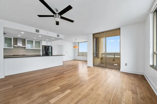 a view of empty room with wooden floor and kitchen view