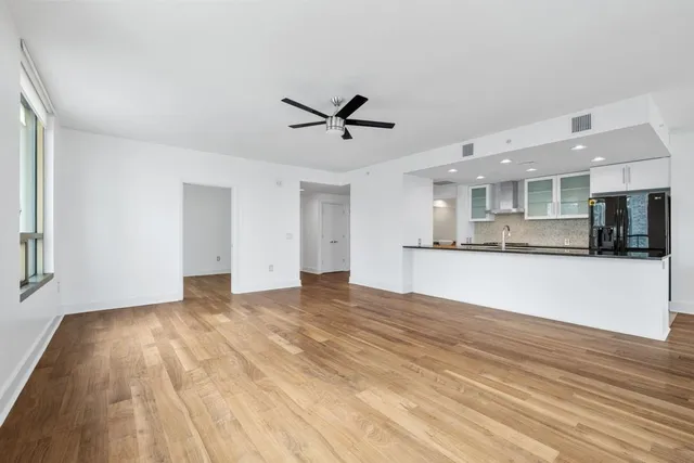 a view of a kitchen with kitchen island wooden floor and stainless steel appliances