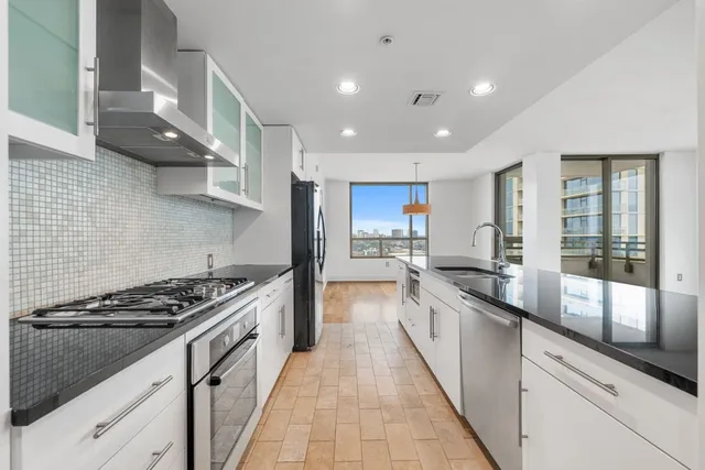 a large kitchen with stainless steel appliances granite countertop a lot of counter space and a sink