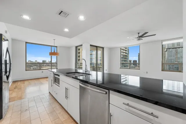 a large white kitchen with stainless steel appliances granite countertop a sink and a stove