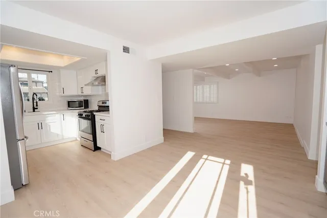 a view of a kitchen with wooden floor and electronic appliances