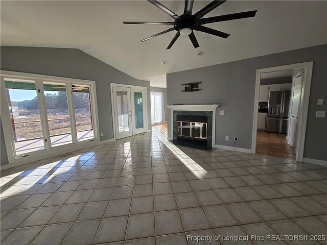 a view of a livingroom with a fireplace a ceiling fan and windows