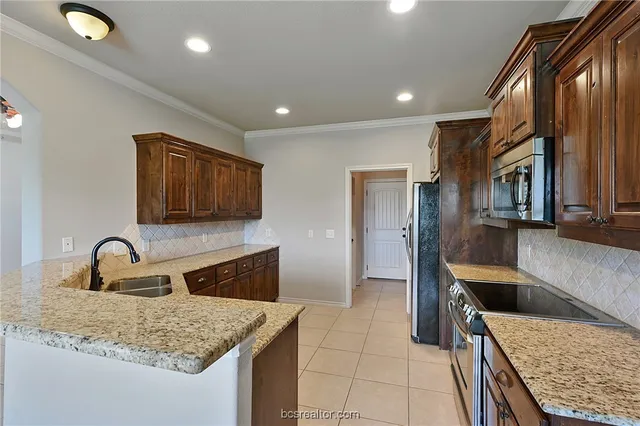 a kitchen with stainless steel appliances granite countertop a sink refrigerator and microwave