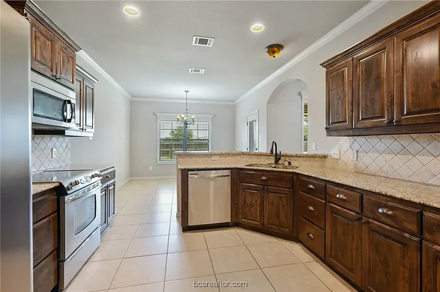 a kitchen with stainless steel appliances granite countertop a stove sink and cabinets