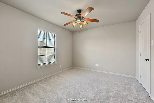 an empty room with window and ceiling fan