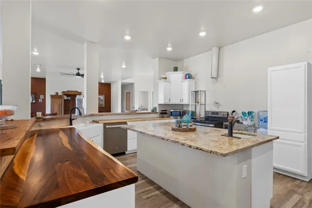 a kitchen with sink stove and white cabinets with wooden floor