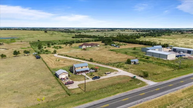 an aerial view of house with yard and trees all around