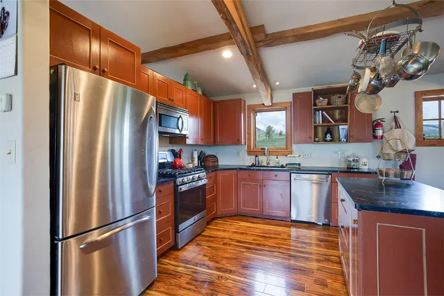 a kitchen with stainless steel appliances granite countertop a refrigerator a stove and a sink with wooden floor