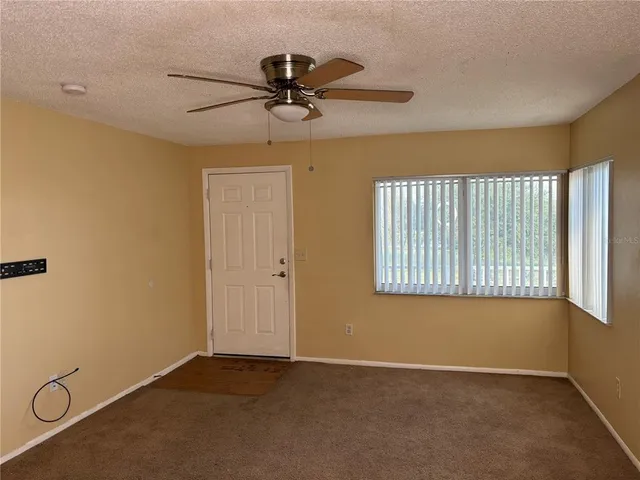 an empty room with windows and a ceiling fan