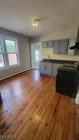 a living room with hard wood floors and a kitchen