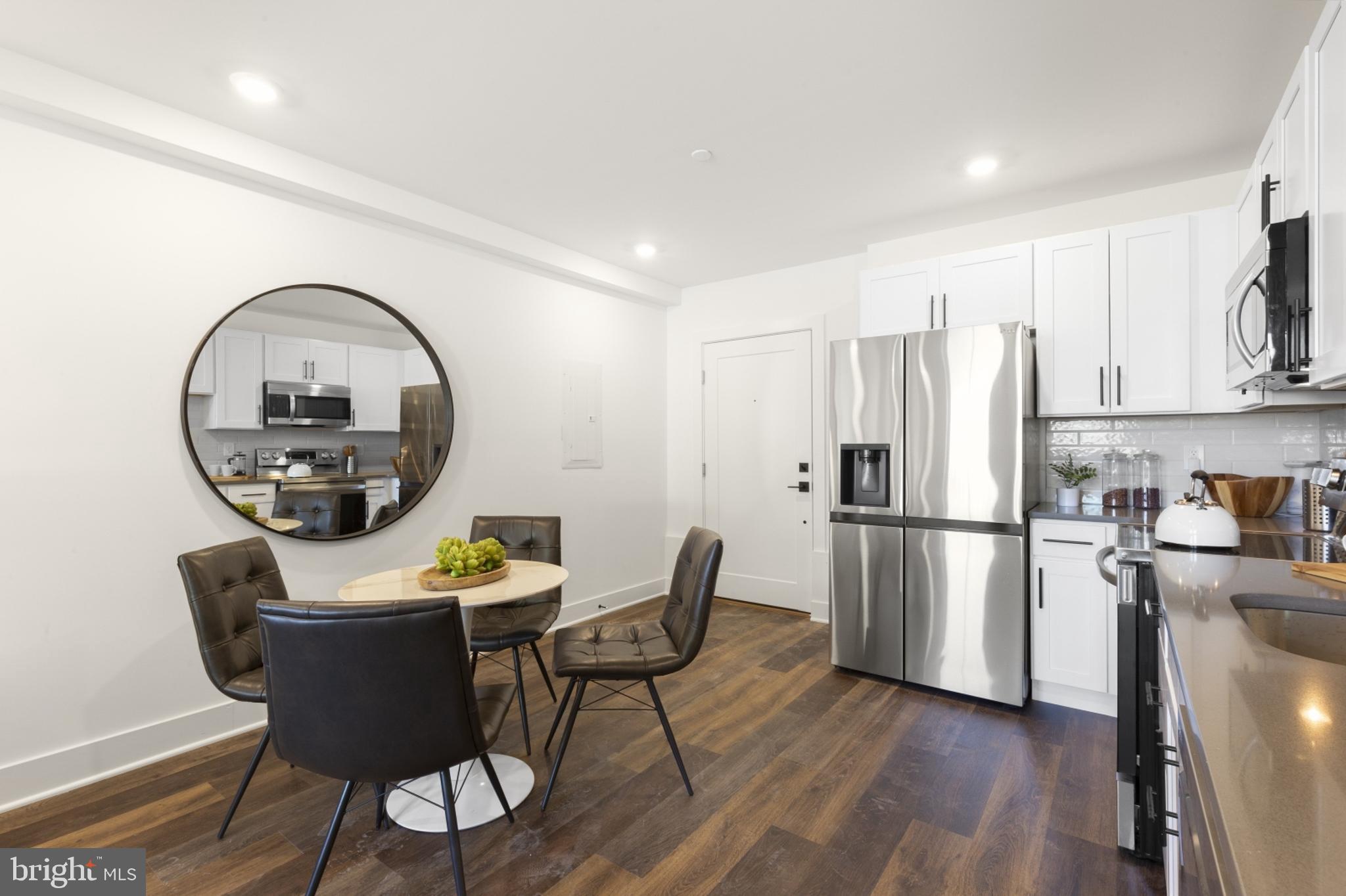 7037 Ridge Avenue, Unit 103 Philadelphia, PA 19128 - Photo 6 of 19 a kitchen with a refrigerator a stove a dining table and chairs