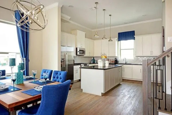 a kitchen with stainless steel appliances granite countertop a refrigerator a sink dishwasher a stove and white cabinets with wooden floor