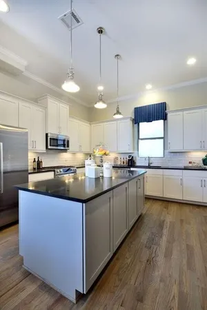 a kitchen with stainless steel appliances granite countertop wooden cabinets a sink a center island and a window
