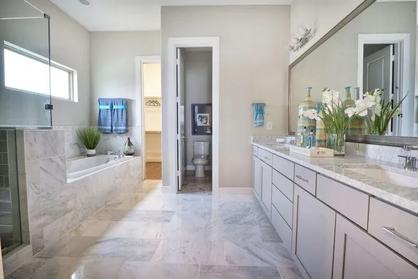 a bathroom with a granite countertop double vanity sink a bathtub and a mirror
