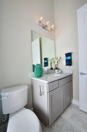 a bathroom with a granite countertop toilet sink and mirror