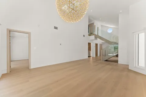an empty room with a fireplace and chandelier fan