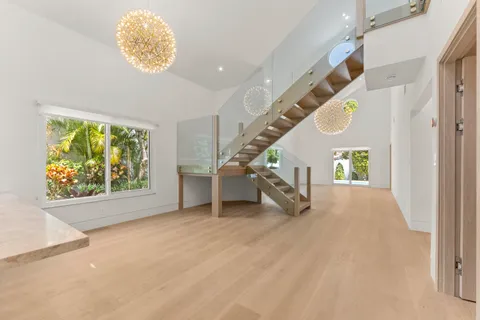 a view of an empty room with stairs and a chandelier