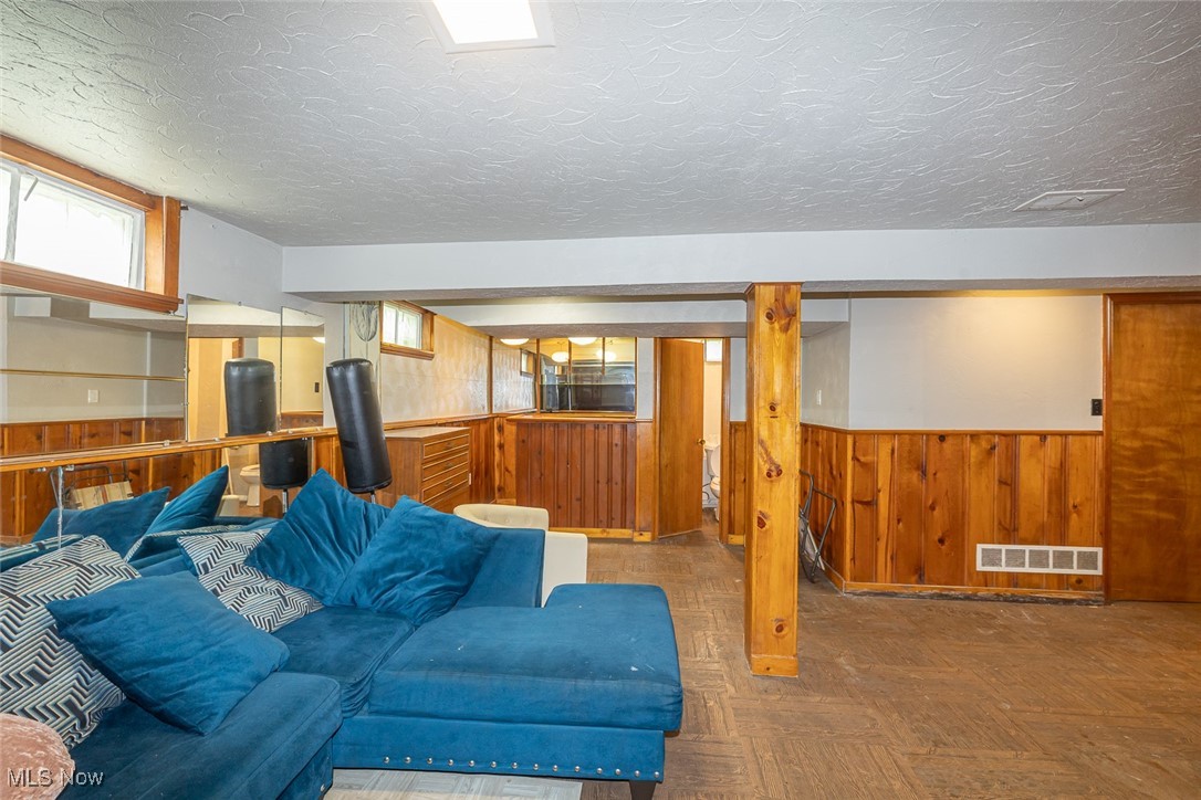21202 Franklin Road Maple Heights, OH 44137 - Photo 21 of 28 Living room featuring wooden walls, wainscoting, and a textured ceiling