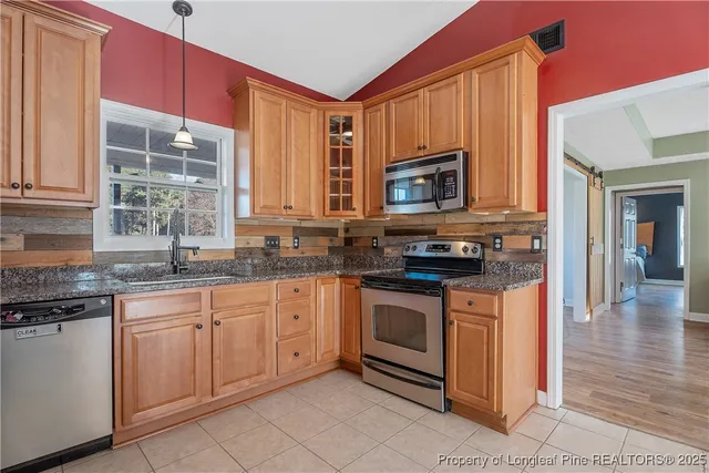 a kitchen with stainless steel appliances granite countertop a stove a sink and a microwave