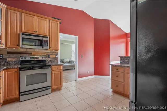 a kitchen with granite countertop a stove top oven microwave and cabinets