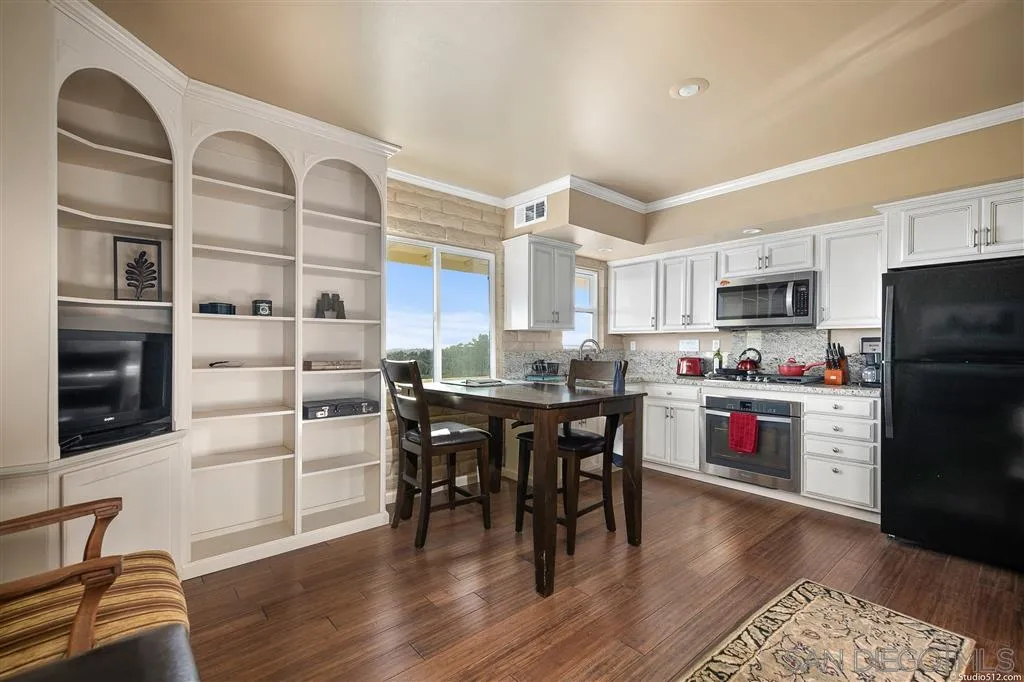 15738 Vesper Road Valley Center, CA 92082 - Photo 19 of 25 a kitchen with stainless steel appliances kitchen island granite countertop a refrigerator a stove a microwave oven a sink with island and chairs