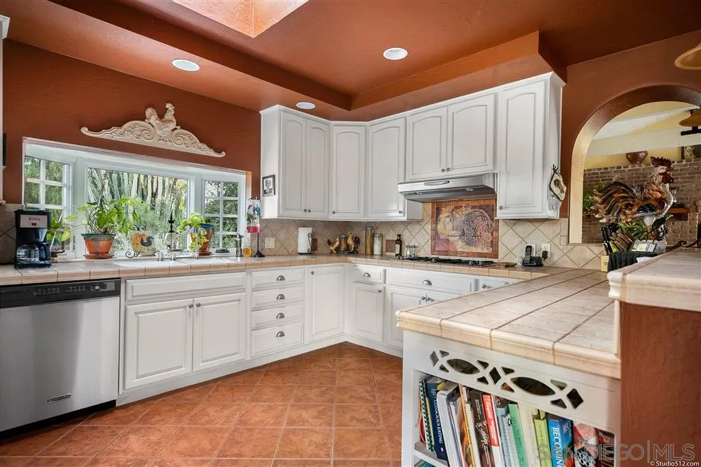 15738 Vesper Road Valley Center, CA 92082 - Photo 8 of 25 a kitchen with stainless steel appliances granite countertop a stove a sink dishwasher and white cabinets with wooden floor