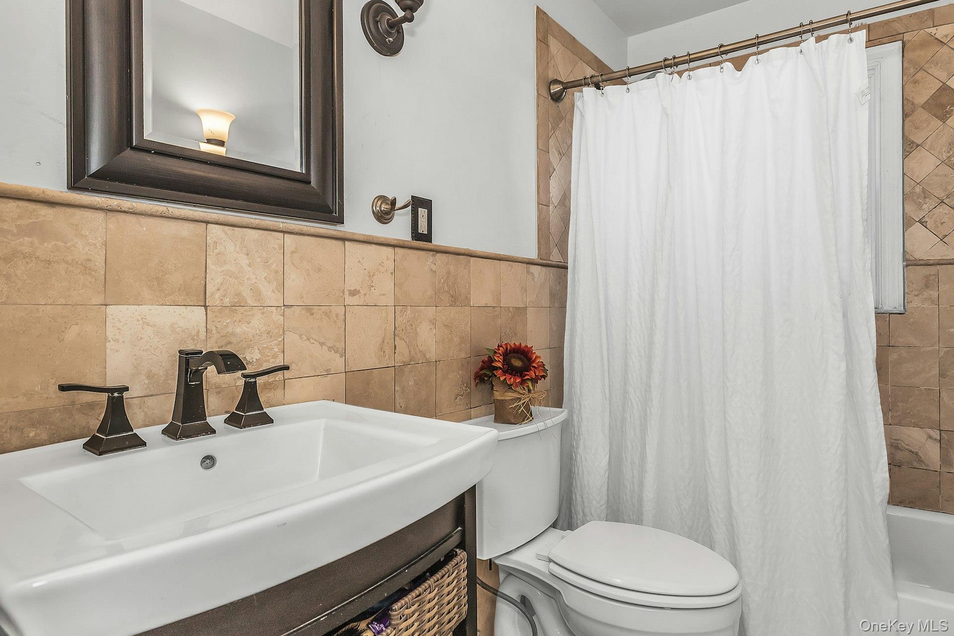 3348 3rd Street Oceanside, NY 11572 - Photo 15 of 32 a bathroom with a sink a toilet and shower curtain