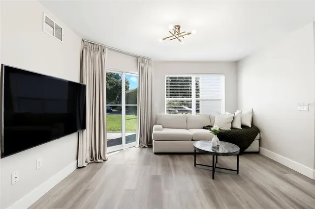 a living room with furniture a flat screen tv and a floor to ceiling window