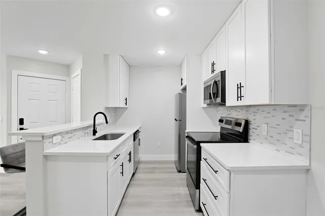 a kitchen with a sink white cabinets and stainless steel appliances