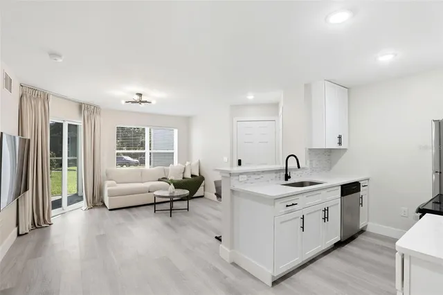 a view of kitchen with stainless steel appliances granite countertop a sink and dishwasher with wooden floor