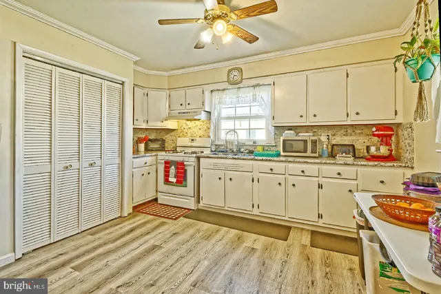 a kitchen with stainless steel appliances granite countertop a stove a sink and white cabinets with wooden floor