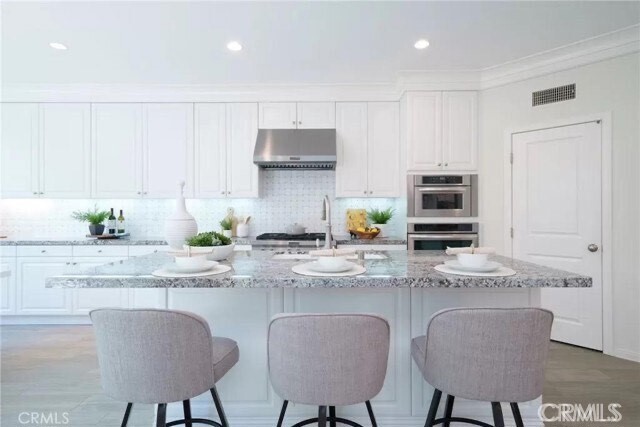 216 Midvale Irvine, CA 92620 - Photo 4 of 9 a kitchen with stainless steel appliances granite countertop a stove a sink a white cabinets a dining table and chairs