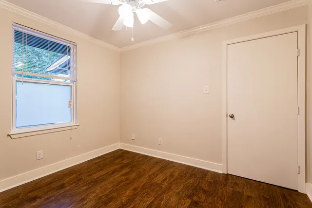 an empty room with wooden floor closet and windows