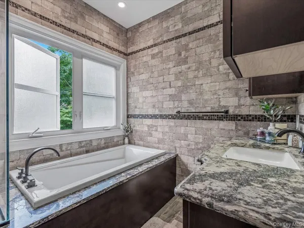 a bathroom with a granite countertop sink and a bathtub