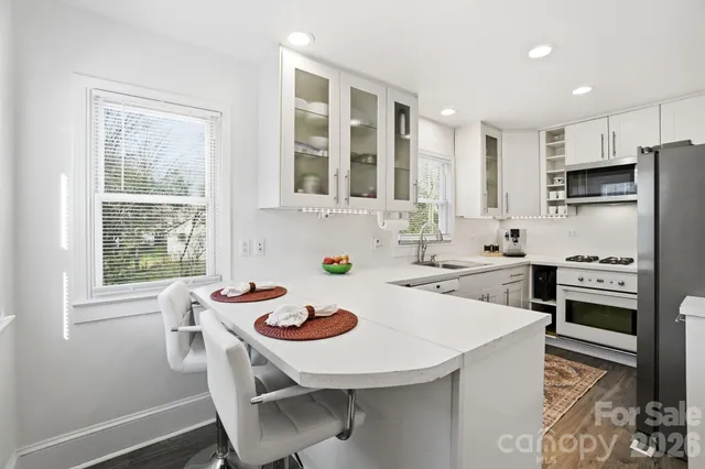 a kitchen with refrigerator a stove a sink and white cabinets with wooden floor