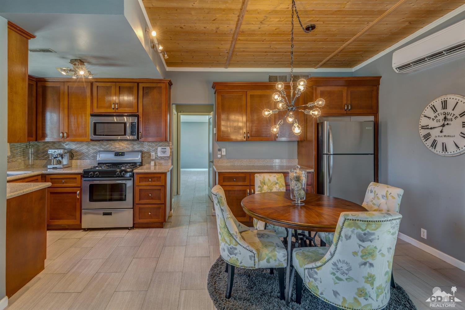 1950 North Magnolia Road Palm Springs, CA 92262 - Photo 10 of 36 a kitchen with stainless steel appliances kitchen island granite countertop a table chairs in it and wooden floors