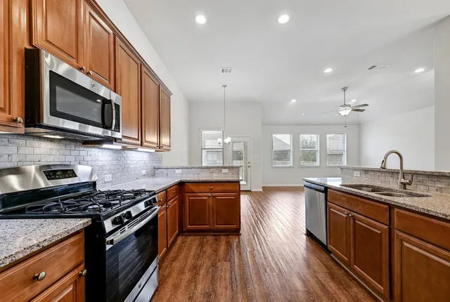 a kitchen with stainless steel appliances granite countertop wooden cabinets stove top oven and sink