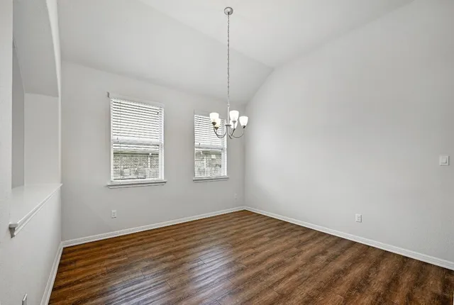 a view of a room with kitchen island stainless steel appliances wooden floor and a chandelier
