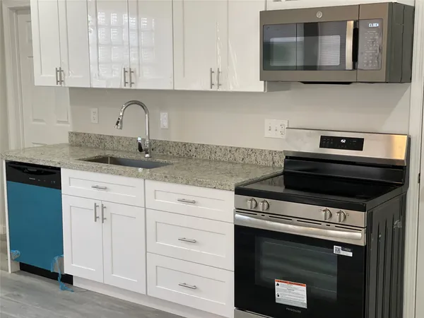 a kitchen with granite countertop white cabinets and stainless steel appliances