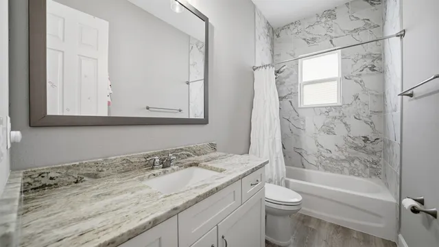 a bathroom with a granite countertop sink toilet and shower
