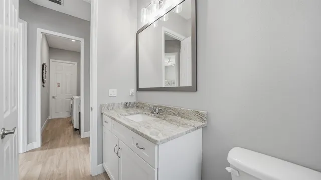 a bathroom with a granite countertop sink a toilet and a mirror