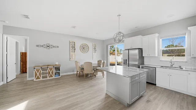 a living room with stainless steel appliances granite countertop furniture wooden floor and a chandelier
