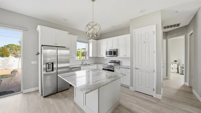 a kitchen with stainless steel appliances granite countertop a refrigerator a stove a sink and white cabinets