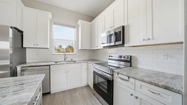 a kitchen with stainless steel appliances granite countertop a sink a stove and a microwave