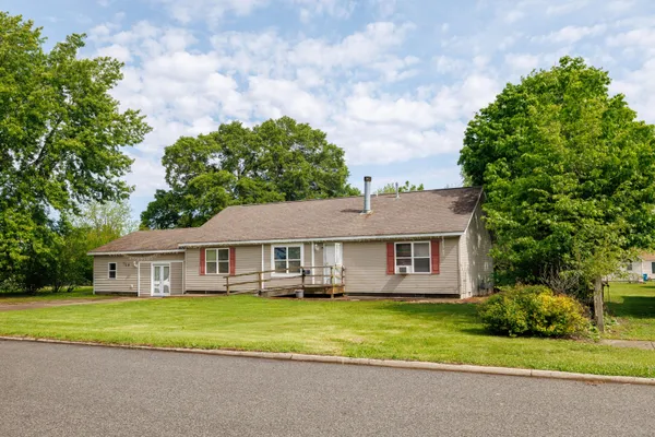 a view of house in front of a big yard with large trees